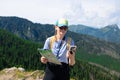 Woman traveler explorer with backpack with phone hiking to the top of the mountain.Shot of a young lost woman holding a Royalty Free Stock Photo