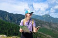 Woman traveler explorer with backpack with phone hiking to the top of the mountain.Shot of a young lost woman holding a Royalty Free Stock Photo