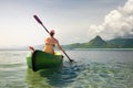 Woman traveler exploring calm tropical beach by canoe.