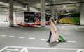 Woman traveler with ffp2 respirator going trough bus station with luggage. Traveling during covid pandemic.