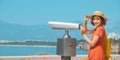 Woman traveler in hat looking through tourist binoculars at a tropical resort Royalty Free Stock Photo