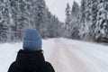 Woman traveler looking into distance at moving car while standing on snowy road in winter forest Royalty Free Stock Photo