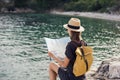 Young woman traveler with backpack holding map by the sea. Travel, tourism, summer holidays concept. Royalty Free Stock Photo