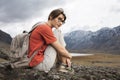 Woman traveler looks into the distance on the snowy mountains. Summer clothes and a backpack on the shoulders.