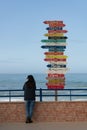 Woman traveler near Indication arrows to cities around the world in Torres Vedras, Portugal