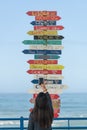 Woman traveler photographing Indication arrows to cities around the world in Torres Vedras, Portugal