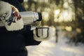 Woman traveler pours hot tea from a thermos into a mug