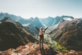 Woman traveler raised arms standing alone on cliff