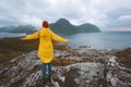 Woman traveler raised hands enjoying rainy mountains view traveling in Norway