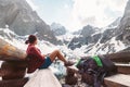 Woman traveler sits on rest point near mountain lake with beautiful view on snowy peaks