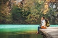 Woman traveler sits on wood bridge on mountain lake at sunny autumn day Royalty Free Stock Photo