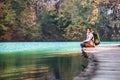 Woman traveler sits on wood bridge on mountain lake at sunny autumn day Royalty Free Stock Photo