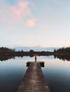 Woman traveler standing alone on pier enjoying sunset lake and forest Royalty Free Stock Photo