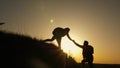 Woman traveler stretches a hand to a man climbing to the top of a hill. travelers climb the cliff holding hands