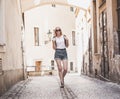 Woman traveler walking through arcade in european historic city. Hipster girl traveling in Europe.