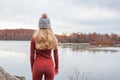 Woman traveler in warm hat and autumn clothes looking at amazing lake and forest, wanderlust travel concept