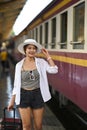 Woman traveler wearing white hat walking with her suitcase at platform. Royalty Free Stock Photo