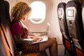 Woman traveling on the airplane flight and working on a laptop with internet on board new technology for aircraft - People love to