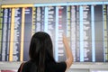 Woman traveller checking flight a departures board at the airpor