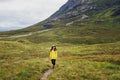 Woman traveller in hat and raincoat hiking in the rainy mountains