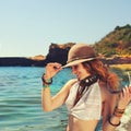 Woman traveller hiking near the sea beach, smiling and beautiful, dressed in boho chic bracelets and hat, Royalty Free Stock Photo