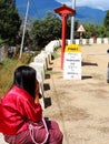 Solo woman traveller and signboard mentioning distance to destination - Bhutanese woman