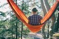 Woman traveller sits in tourist hammock in sunny pine forest enjoying her loneliness, sense of peace and serenity. Natural moments