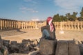 A woman traveller sitting on rock looking at Roman column in Jerash Roman ruin and ancient city in Jordan