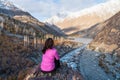 A woman traveller sitting on rock and looking to beautiful mountain landscape in autumn season in Gupis valley, Pakistan