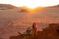 A woman traveller sitting on rock up on hill and enjoying beautiful sunset in Wadi Rum desert, Jordan, Arab Royalty Free Stock Photo