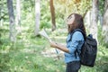 Woman traveller using map in green natural park trekking alone happy, carefree enjoy backpack outdoor lifestyle. Asian woman