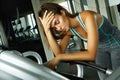 Woman on the treadmill with overtraining symptoms in gym