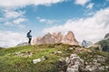 Woman trekker with backpack and trekking poles on green hill enjoying picturesque Dolomite Alps view near Tre Cime di Lavaredo