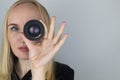 A woman tries on a camera lens instead of an eye. The concept of the photographer`s work and the creative approach to photography