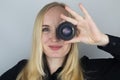 A woman tries on a camera lens instead of an eye. The concept of the photographer`s work and the creative approach to photography