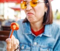 Woman tries to eat a spoiled sausage, disgusting unhealthy fast food Royalty Free Stock Photo