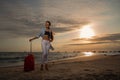 Woman on tropical beachin hat with large red suitcase Royalty Free Stock Photo