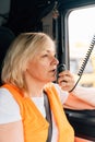 Woman truck driver talking by radio inside the cabin. Female trucker job worker Royalty Free Stock Photo