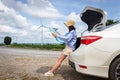 woman in the trunk of a car looking at a map to reach the holiday destination with blue sky Royalty Free Stock Photo