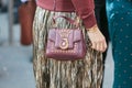 Woman with Trussardi dark red bag, metallic pleated skirt and golden Cartier bracelet before Trussardi Royalty Free Stock Photo