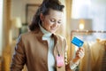 Woman trying coat with sale price tag and holding credit card Royalty Free Stock Photo