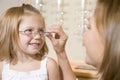 Woman trying glasses on young girl at optometrists