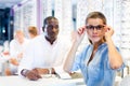 Woman trying on a spectacles in medical shop, male optician Royalty Free Stock Photo