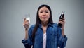 Woman trying to chose between unhealthy carbonated drink and useful healthy milk