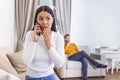 Woman turned her back to man, talking on phone with her lover, boyfriend sitting in the back watching tv. Cheating and infidelity Royalty Free Stock Photo