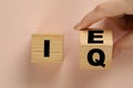Woman turning cube with letters E and I near Q on beige background, top view