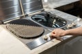 Woman turning on electric kitchen built-in grill