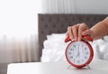 Woman turning off alarm clock on table in bedroom. Royalty Free Stock Photo