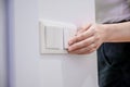 A woman turns off the home light switch when she leaves the room. Power, energy saving, energy saving