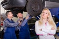 Woman and two auto mechanics Royalty Free Stock Photo